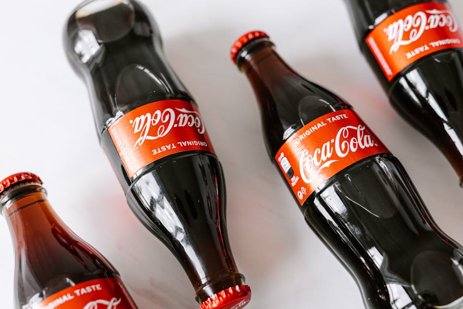 From above of glass bottles full of soft coke drink placed on white background